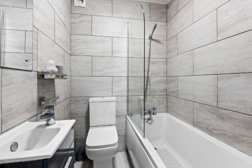 uma casa de banho com uma banheira, um WC e um lavatório. em Cosy 2 Bedroom Flat in East Ham, Close to Excel em Londres