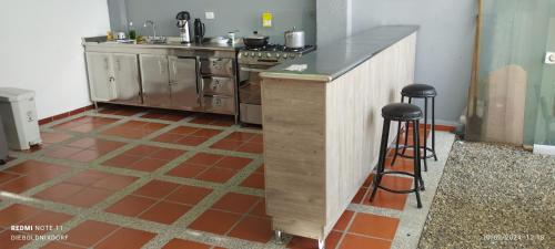 - une cuisine avec une cuisinière et un comptoir avec des tabourets dans l'établissement Habitaciones Cataleya Valledupar, à Valledupar