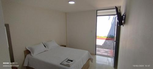 a bedroom with a white bed and a window at Habitaciones Cataleya Valledupar in Valledupar