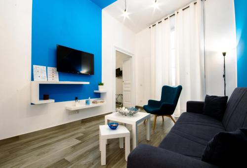 un soggiorno con pareti blu, divano e sedie di Casa Cosmedin a Napoli