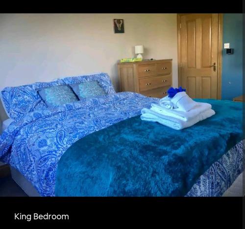 a blue bed with a blue comforter and towels on it at Scrabo View - King Bedroom with private bathroom in Comber