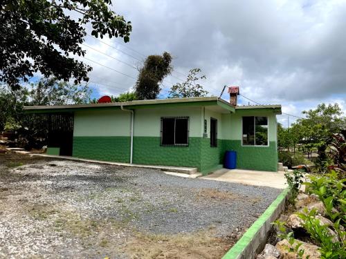 une maison verte avec une allée en face de celle-ci dans l'établissement Miravalles Volcano House, à Guayabal