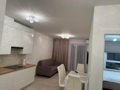 a kitchen and a living room with a couch and a table at Apartament JANICKIEGO 159 parking free in Poznań