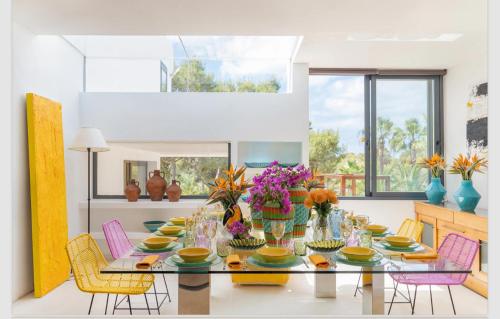 a dining room with a table with colorful chairs at Villa Leonor in Es Caló