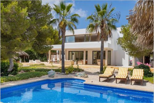 a house with a swimming pool and palm trees at Villa Leonor in Es Calo