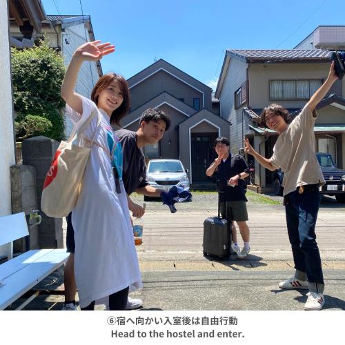 a group of people standing in a parking lot with their arms up at Backpackers Hostel TSUBAMENOYADO in Shizuoka
