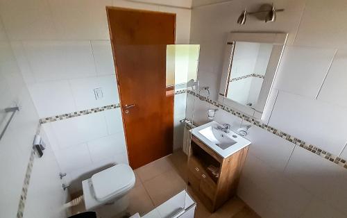 a bathroom with a toilet and a sink and a mirror at Cabañas & Apart Del Sauce in El Hoyo