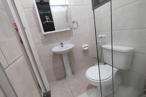 a white bathroom with a toilet and a sink at Solares Boa Estada in Búzios