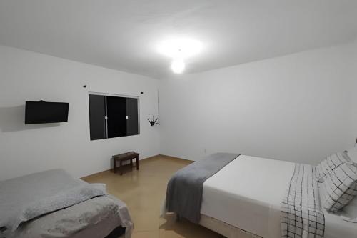 um quarto branco com uma cama e uma televisão em Solares Boa Estada em Búzios