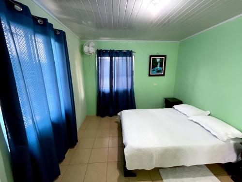 a bedroom with a white bed and blue curtains at Miravalles Volcano House in Guayabal