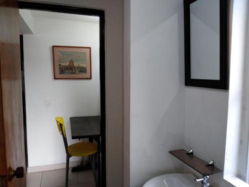 ein Badezimmer mit einem Spiegel, einem Waschbecken und einem Stuhl in der Unterkunft Hostal Norma101 in Bogotá