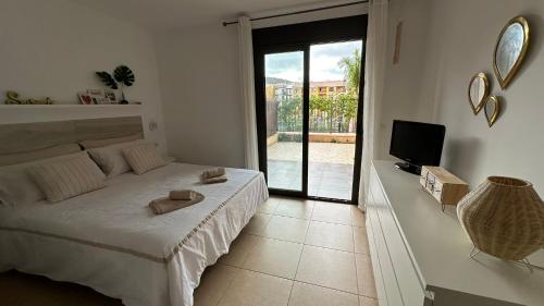 a white bedroom with a bed and a television at Cómodo apartamento en El Palm mar in Palm-Mar