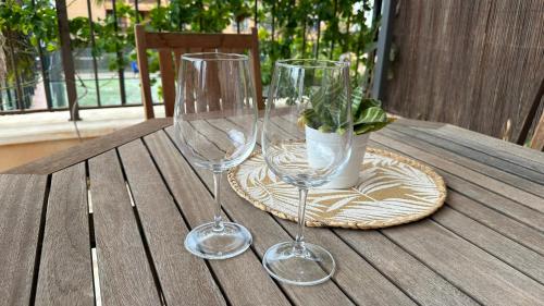 two wine glasses and a potted plant on a wooden table at Cómodo apartamento en El Palm mar in Palm-Mar
