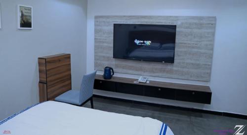a bedroom with a bed and a tv on a brick wall at The Zodiac House. in Lekki