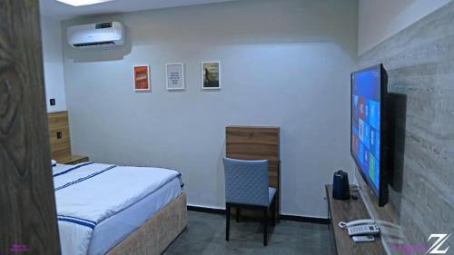 - une chambre avec un lit, une télévision et une chaise dans l'établissement The Zodiac House., à Lekki
