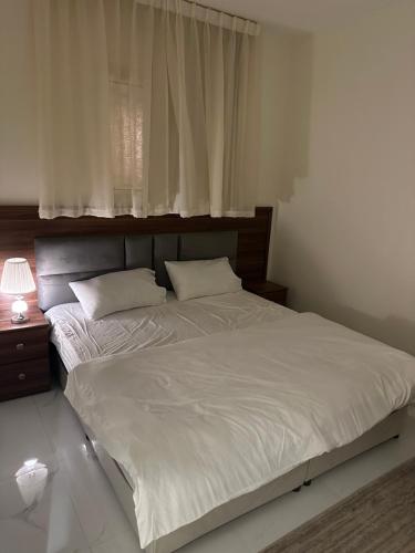 een slaapkamer met een groot wit bed en een raam bij شقة فاخرة بدخول ذاتي 2 in Al Kharj