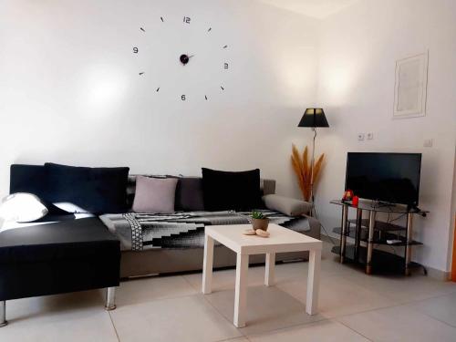 un soggiorno con divano e orologio sul muro di 4T apartments ad Argostoli
