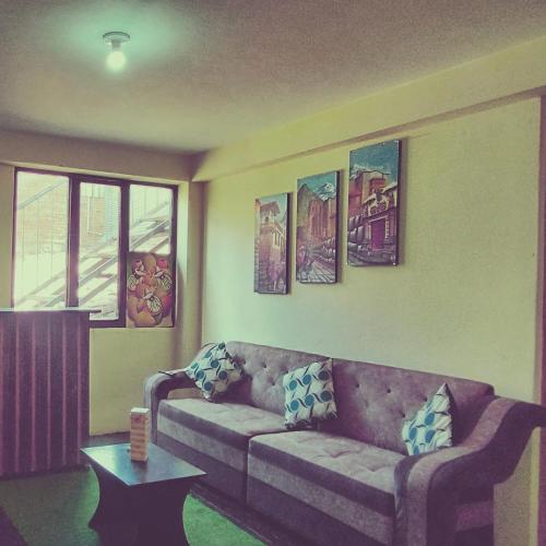 sala de estar con sofá y pinturas en la pared en MEDIA LUNA apart, en Cusco