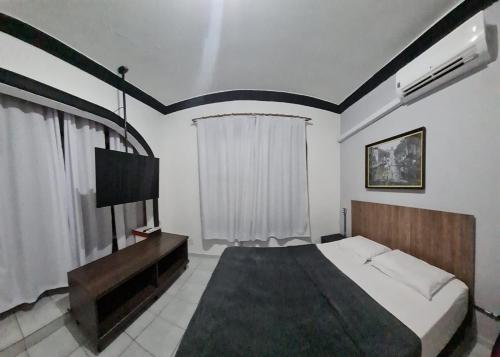 a bedroom with a large bed and a television at Pousada - Aqui Hostel in Bragança Paulista