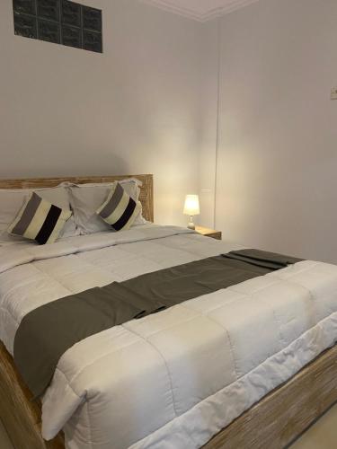 a bedroom with a large white bed with a lamp at Tirta Kemala House in Ubud