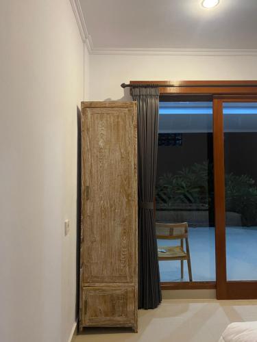 a wooden cabinet in a room with a window at Tirta Kemala House in Ubud