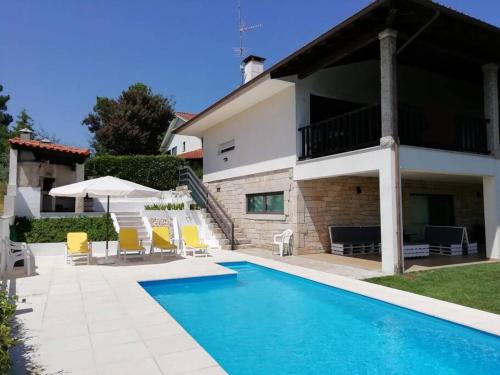 a villa with a swimming pool in front of a house at Casa da Encosta Chaves in Chaves