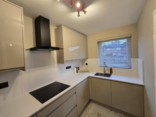 Una cocina con gabinetes blancos y un fregadero y una ventana. en New 2 Bedroom Appartment In Manchester - Stretford - Old Trafford Close to Football-Cricket Ground & City Centre, en Mánchester