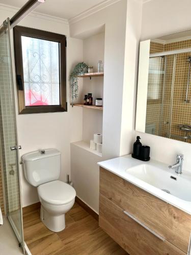 a bathroom with a toilet and a sink and a window at Bungalow en Denia in Denia