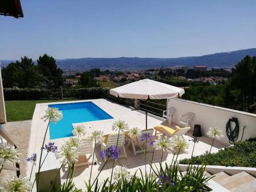 eine Villa mit einem Pool und einem Sonnenschirm in der Unterkunft Casa da Encosta Chaves in Chaves