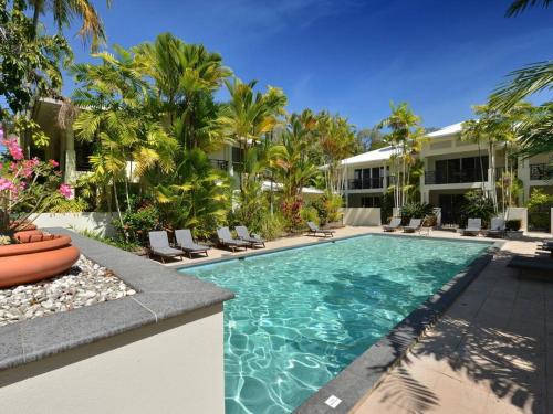 a swimming pool in front of a building with palm trees at Plantation Villa No.8 - Spacious Villa by the Beach in Port Douglas