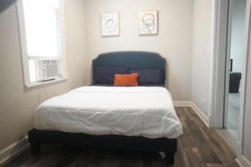 a bedroom with a bed with an orange pillow on it at Cozy Apt Near Midway Airport & Downtown in Chicago