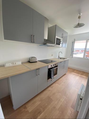 a kitchen with white cabinets and a wooden floor at Appartement 59m2 professionnel ou familial Saint Quentin en Yvelines in Montigny-le-Bretonneux