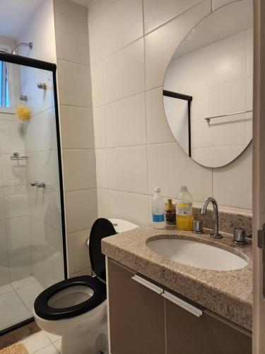 a bathroom with a toilet and a sink and a mirror at Loft Ilha Pura in Rio de Janeiro