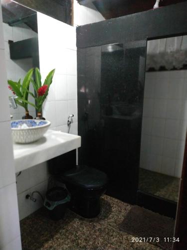 a bathroom with a black toilet and a sink at Casa Sanca in Rio de Janeiro