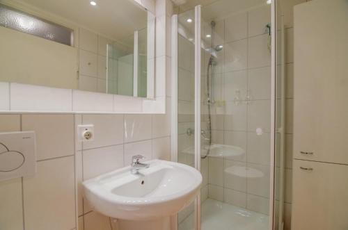 uma casa de banho branca com um lavatório e um chuveiro em Haus-Sylter-Welle-5-49-OB em Westerland
