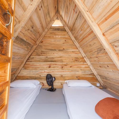 a room with two beds in a wooden cabin at Hostel Costa Terral in Matinhos