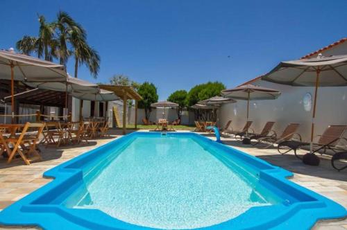 uma piscina azul com cadeiras e guarda-sóis em Hostel Costa Terral em Matinhos