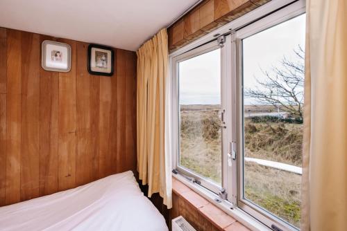 a bedroom with a bed and a large window at Villa Zuidwest 6, Garden, Dunes & Free parking in Zandvoort
