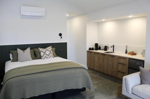 a bedroom with a large bed and a sink at Ahuru House in Mangawhai