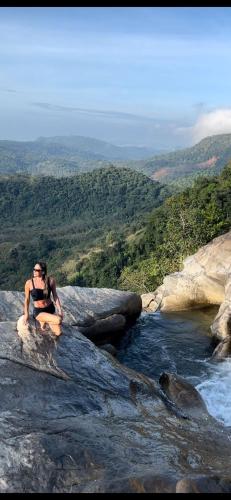 a woman sitting on a rock near a river at Diyaluma View Cotage in Koslanda