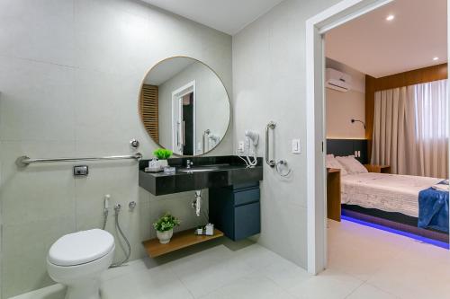 a bathroom with a sink and a toilet and a bed at Confortável Studio com 46,72m² in Florianópolis