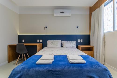a bedroom with a large blue bed with towels on it at Confortável Studio com 46,72m² in Florianópolis