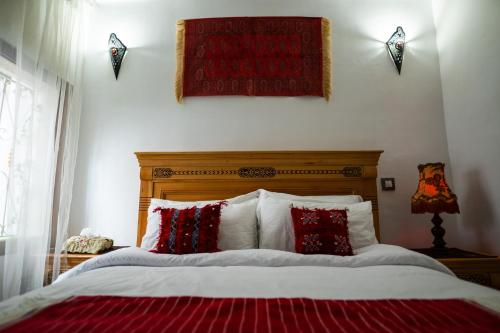 een slaapkamer met een bed met rode en witte kussens bij DAR AYOUB - Entire House Near PALAIS MARCHAN - Updated 2024 in Tanger