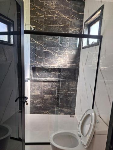 a bathroom with a toilet and a glass shower at Suítes cava da onça in Capitólio