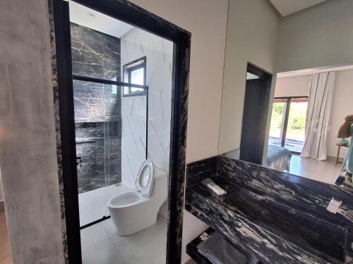 a bathroom with a toilet and a large mirror at Suítes cava da onça in Capitólio