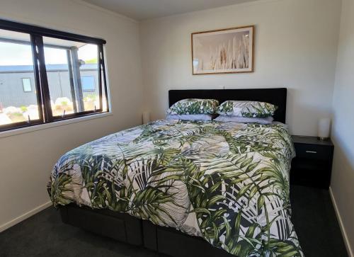 a bedroom with a bed with a green bedspread at Te Tirohanga (The View) in Taumarunui