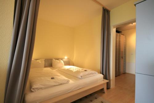 1 cama con sábanas blancas y almohadas en una habitación en Ferienwohnung Panoramablick, en Füssen