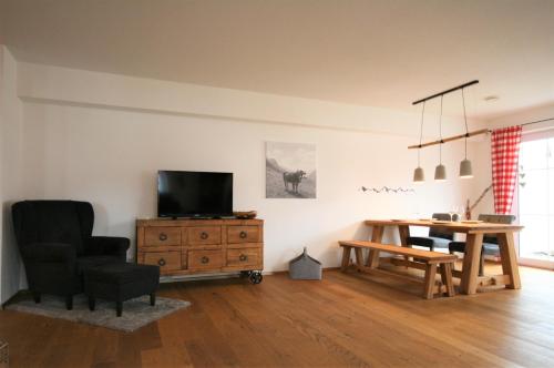 a living room with a television and a wooden table at Allgäustüble am See in Schwangau