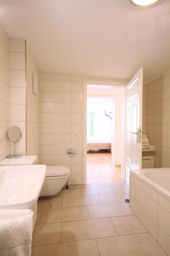 a bathroom with two sinks and a tub and a toilet at Ferienwohnung Alpenrose in Pfronten