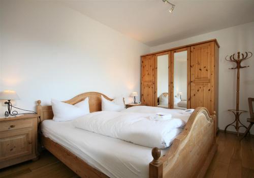una camera da letto con un letto grande con lenzuola bianche di Ferienhaus Seerose a Füssen
